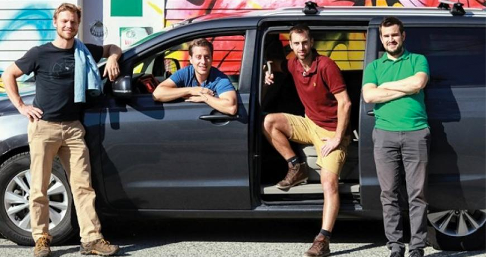 4 men standing in front of a minivan
