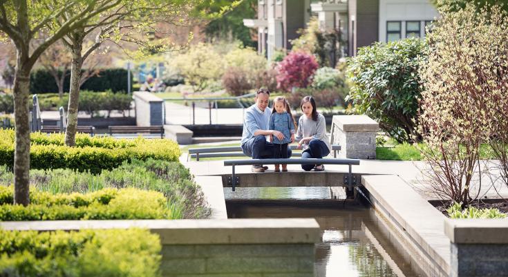 A family walks near a water feature in Wesbrook Place