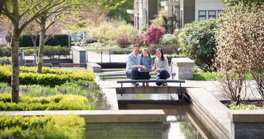 A family walks near a water feature in Wesbrook Place