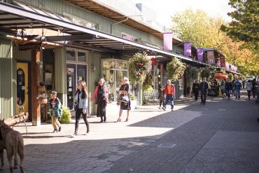 People walking along a pedestrian-only street. Stores are visible along one side of the street.