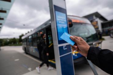 Student showing a compass card in front of a transit stop