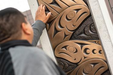 Musqueam artist Brent Sparrow looking at his artwork.