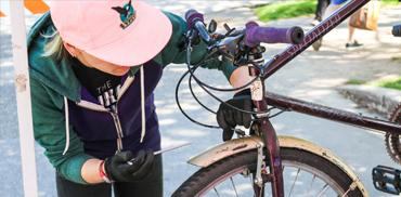 A female student at Bike Kitchen repairs a bike