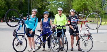 Four people holding up bikes as part of Go By Bike Week.